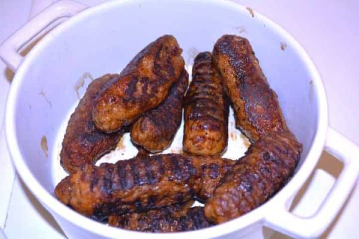 Fried Freshly cooked, tender skinless sausages resting warm in a bowl after pan-frying.