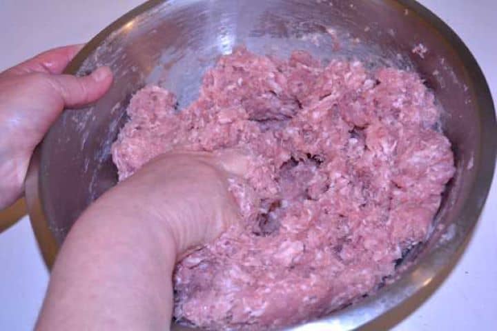 Mixing Mince Hand-mixing minced meat and pork lard together to distribute fat evenly for juicy skinless sausages.
