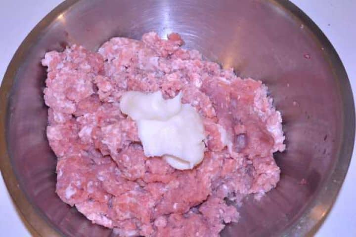 Mince and Lard Adding two tablespoons of pork lard to minced pork and turkey meat in a glass bowl.
