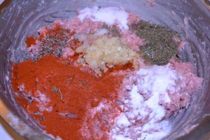 Mince and Spices Adding garlic paste, paprika, summer savory, and sodium bicarbonate on top of the ground meat mixture.