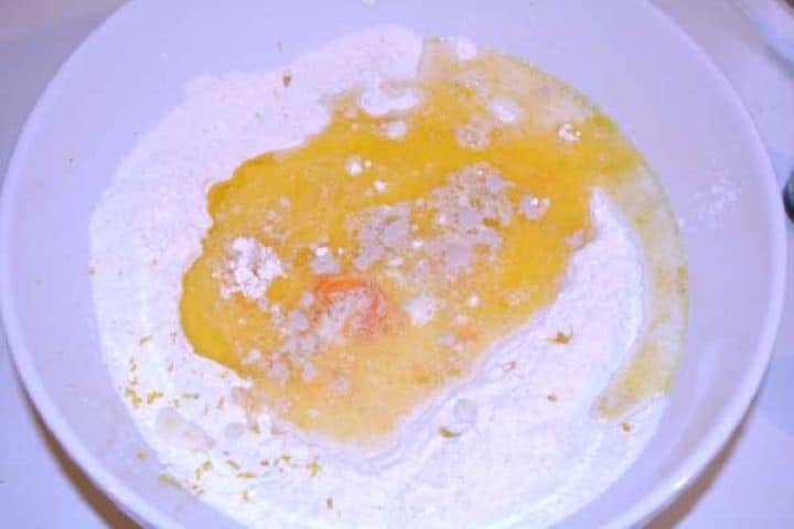 Make the Dough Sifted flour, egg yolks, and melted butter combined in a mixing bowl for homemade doughnut dough.