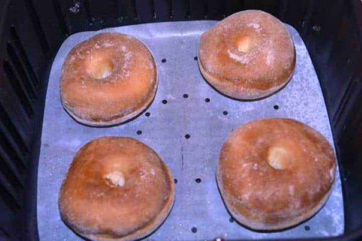 Fried Doughnuts in Basket Golden brown, freshly baked air fryer doughnuts resting in the air fryer basket after cooking.