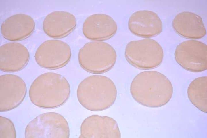 Dough Shape Cut round yeast doughnut dough rings and doughnut holes resting on a floured table for the second rise.