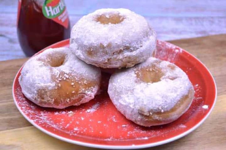 Serving Warm air fryer yeast doughnuts dusted with sweet powdered sugar arranged on a plate.