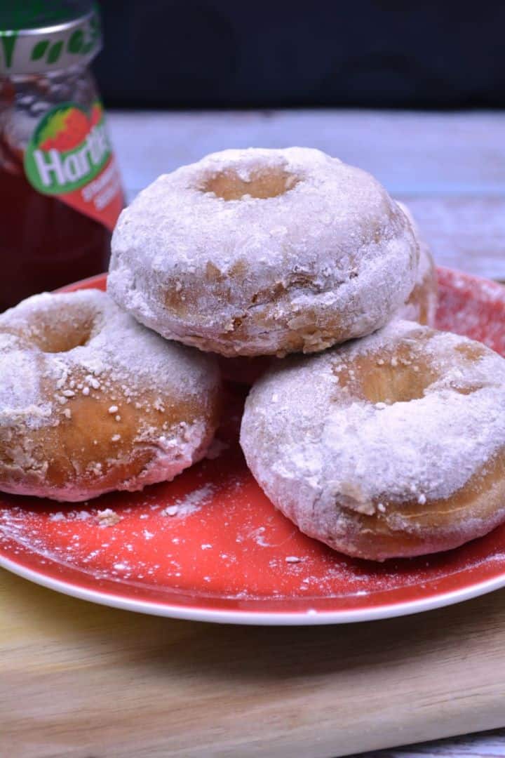 Serve Golden air fryer doughnuts from scratch dusted with powdered sugar and served on a red plate.