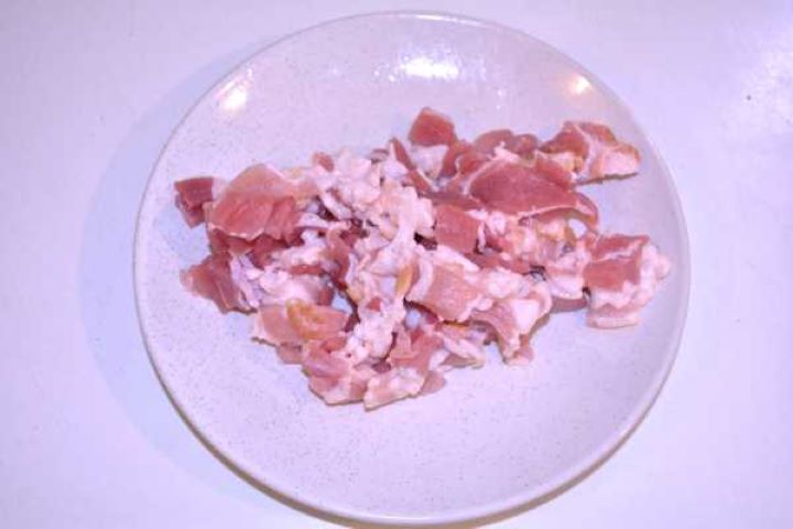 Bacon Diced raw smoked streaky bacon arranged on a plate ready for frying.