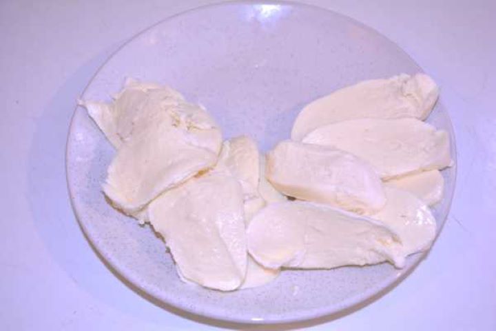 Mozzarella Thick slices of fresh mozzarella cheese patted dry on a plate.