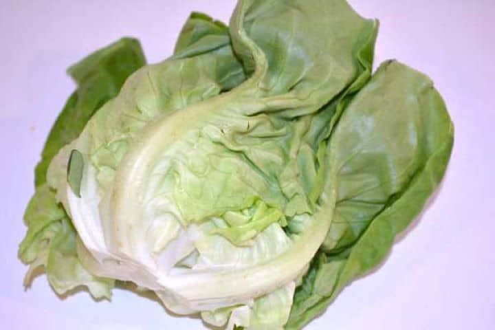 Lettuce Fresh whole head of crisp green butterhead lettuce on a wooden kitchen table.