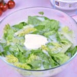 Authentic Hungarian lettuce salad in a glass bowl topped with Greek yogurt and fresh dill.