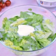 Authentic Hungarian lettuce salad in a glass bowl topped with Greek yogurt and fresh dill.