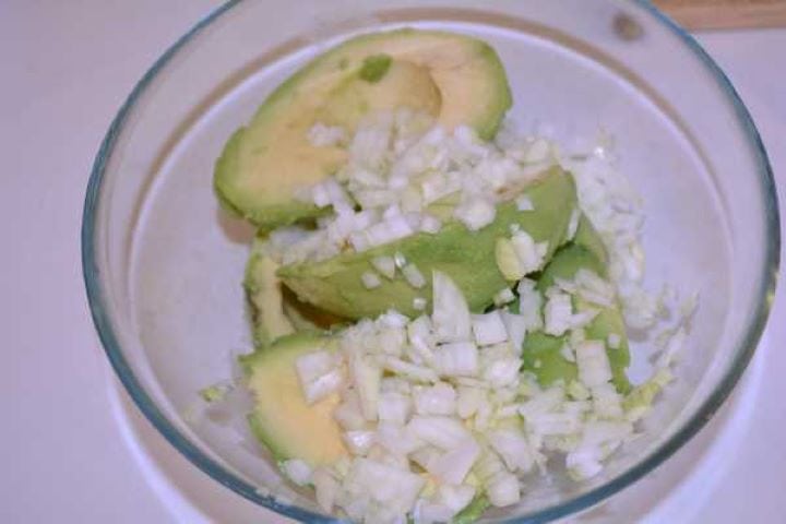 Avocado and Onion Avocado halves and diced onion in a bowl ready for immersion blending.