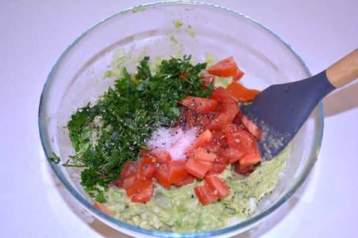 Seasoning Adding diced tomatoes and chopped flat-leaf parsley over mashed avocado.