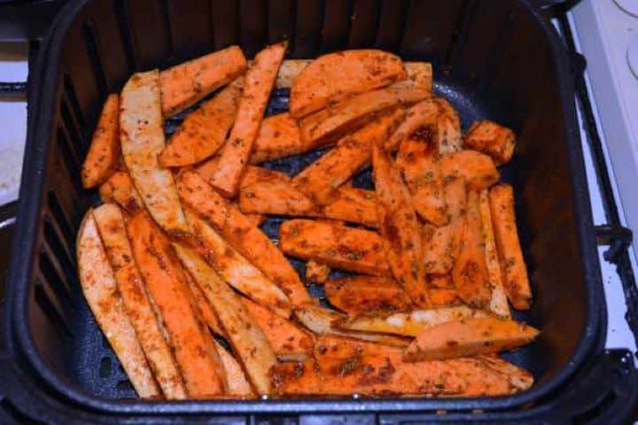 Basket Seasoned sweet potato wedges arranged in a single layer inside a Cosori air fryer basket before cooking.