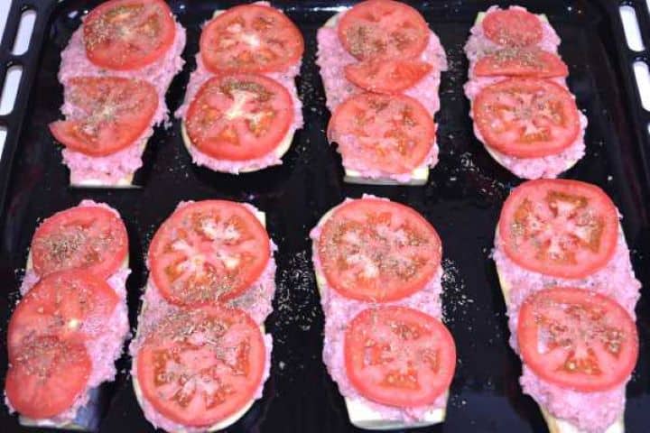 Layer2 Sliced tomatoes and dried oregano layered over seasoned ground pork on eggplant slices before baking.