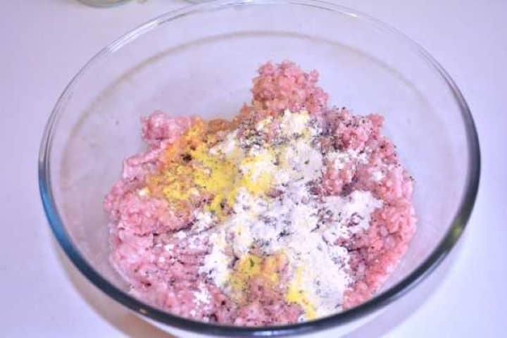 Seasoned Raw pork mince in a bowl seasoned with sea salt, black pepper, onion powder, and dried vegetable mix.