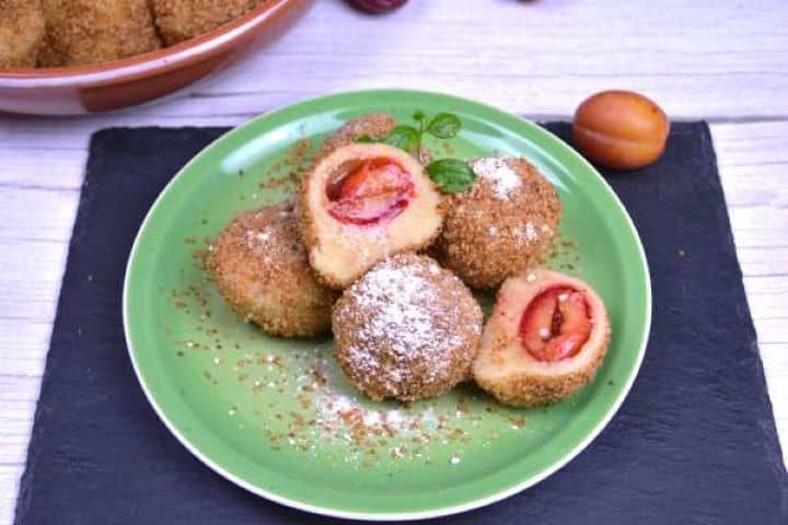 Plate of authentic Hungarian plum dumplings dusted with cinnamon sugar and served warm.