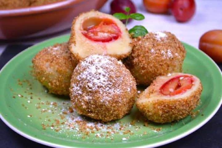 Served Traditional szilvás gombóc sliced open to show the juicy plum center and tender potato dough.