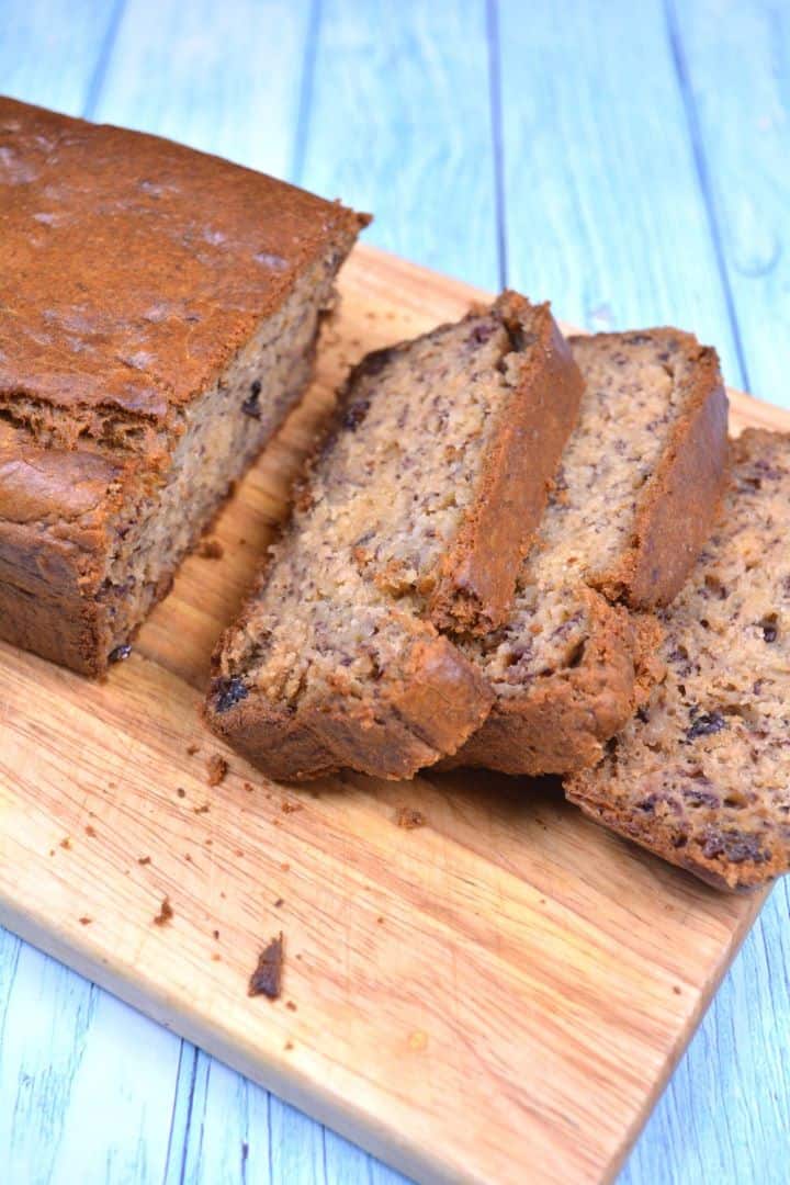 Serving Slices of moist sugar free banana bread with raisins on a wooden cutting board.