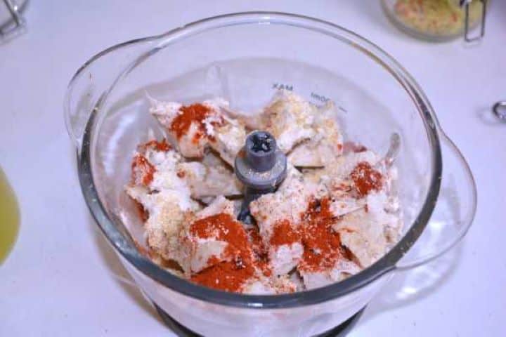 Chopper Chopped chicken breast placed in an electric food chopper with sweet paprika, onion powder, and garlic granules.