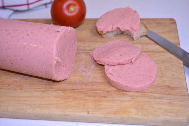 Serve Close-up view of thinly sliced homemade chicken salami showcasing its smooth, rosy deli texture and clean-cut edges.