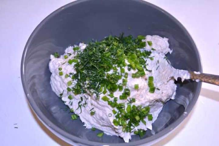Seasoning Chopped dill, chives, and black pepper added to the blended smoked mackerel spread in a mixing bowl.