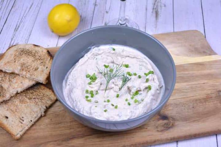 Easy smoked mackerel dip served in a bowl with crisp golden toast triangles and lemon slices.