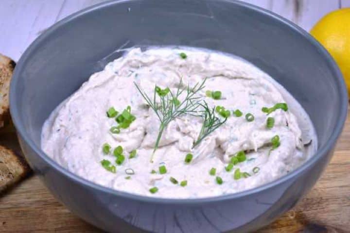 Served Bowl of creamy smoked mackerel spread garnished with cracked black pepper and fresh herbs with toasted baguette slices.