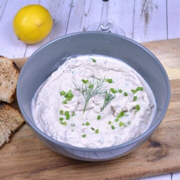 Creamy smoked mackerel spread in a serving bowl garnished with fresh dill and served with toasted bread slices and lemon wedges.
