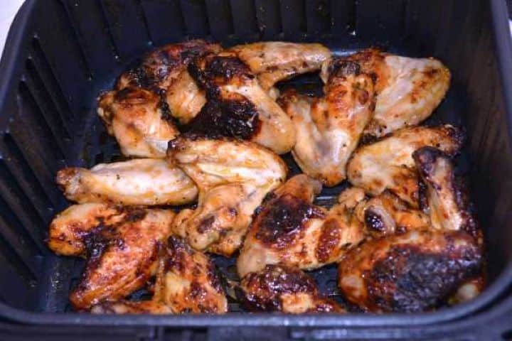 Half Fried Turning partially cooked chicken wings over with kitchen tongs and brushing them with sweet honey glaze.