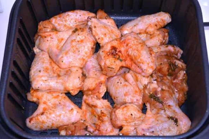 Seasoned chicken wings arranged in a single layer inside the Cosori air fryer basket before cooking.