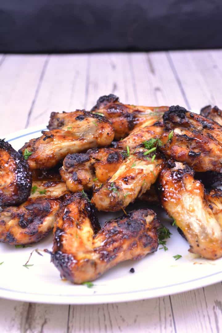 Serving Crispy air fryer honey garlic chicken wings served on a white plate with fresh parsley garnish.