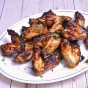 Crispy air fryer honey garlic chicken wings served on a white plate with fresh parsley garnish.