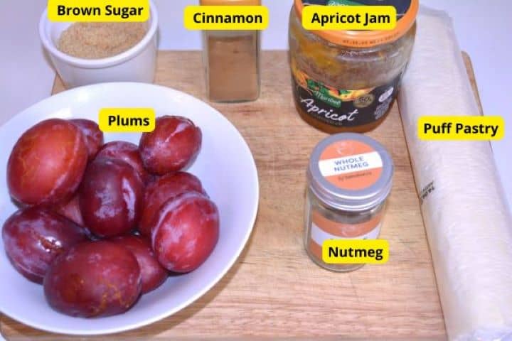 Ingredients Ingredients for puff pastry plum tart including fresh red plums, brown sugar, cinnamon, nutmeg, apricot jam, and puff pastry sheet.