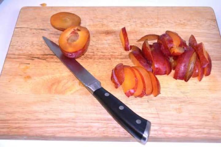 Sliced Plums Evenly sliced plum crescents on a cutting board ready for assembling the fruit tart.