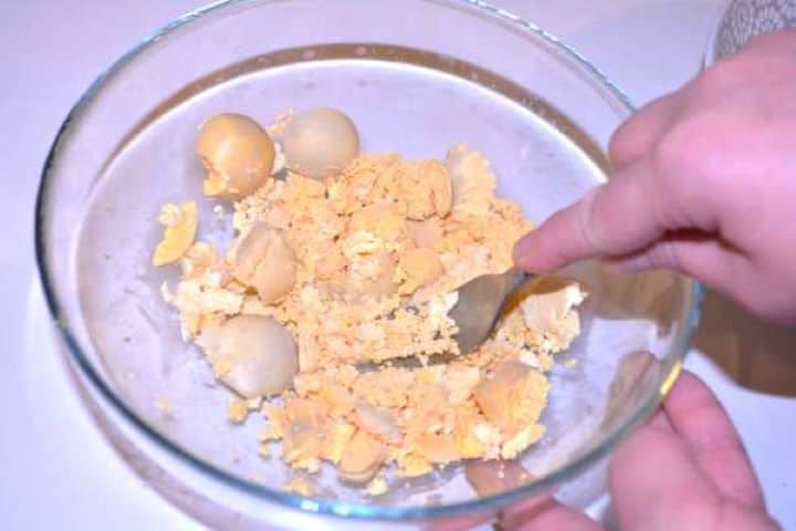 Crush Mashing cooked egg yolks finely with a fork in a glass mixing bowl.