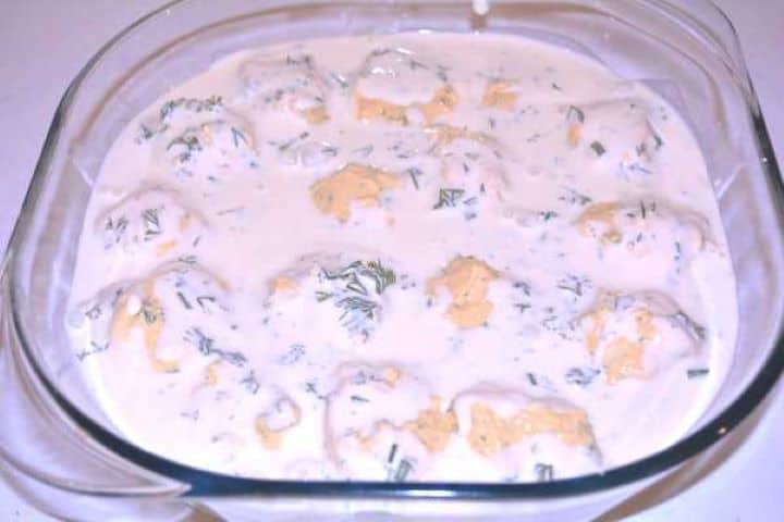 Ready Deviled eggs without vinegar coated in dill sauce resting in a glass dish ready to chill.
