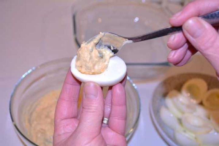 Stuffing Spooning savory yolk filling into hard-boiled egg white halves.