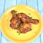 Crispy golden brown air fryer chicken drumsticks served on a yellow plate.