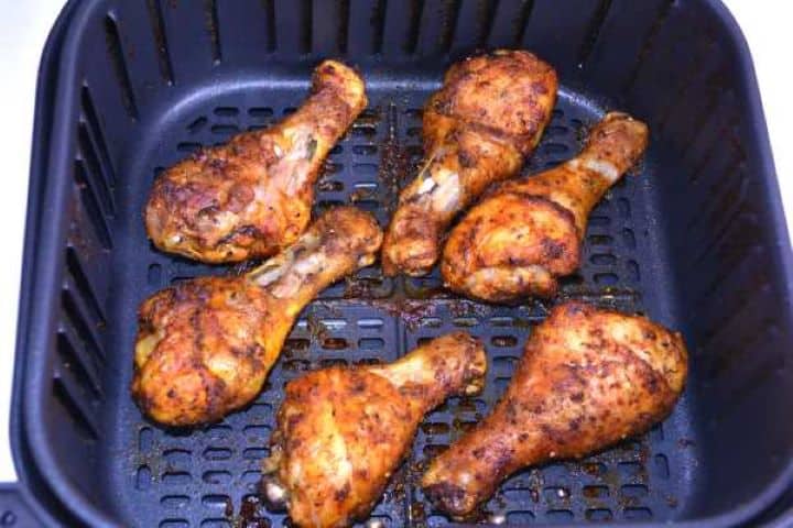 Freshly cooked crispy air fryer chicken drumsticks resting in the basket to lock in juices.