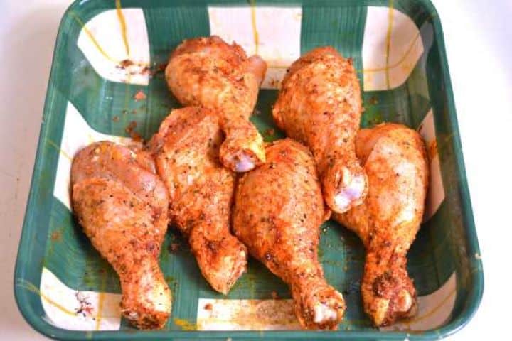 Seasoned Raw chicken drumsticks evenly coated in a vibrant red paprika spice rub ready for air frying.
