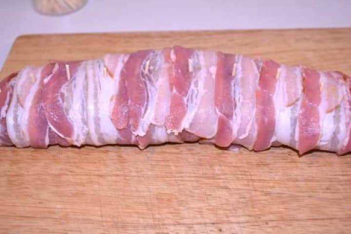 Fixed Wooden half-toothpicks inserted along the bacon-wrapped pork tenderloin roll at one-inch intervals.