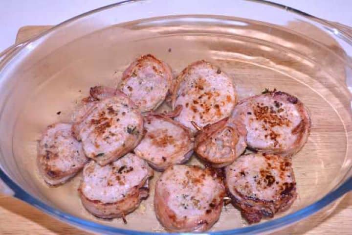Ready Cooked bacon-wrapped pork medallions resting on a plate to redistribute meat juices.