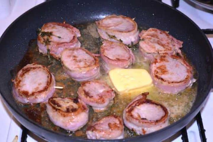 Basted Basting flipped pork medallions with foaming melted butter and fresh thyme sprigs in a skillet.