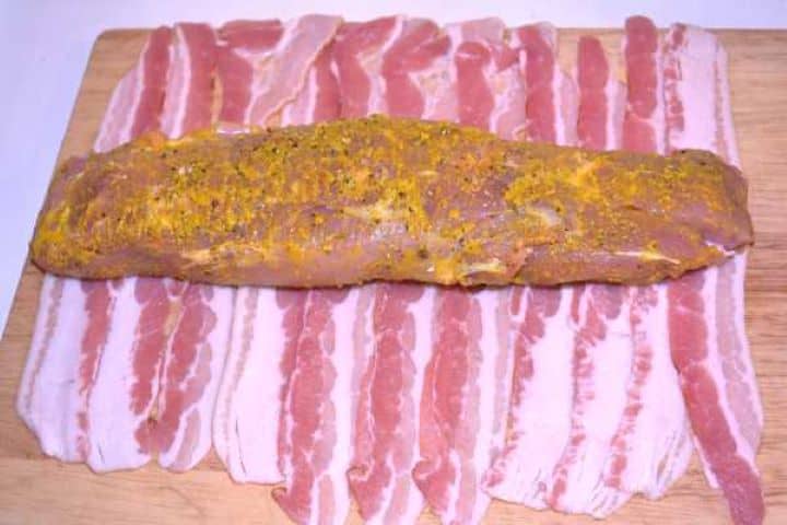 Prepare Mustard-coated pork tenderloin centered across overlapping strips of smoked bacon.