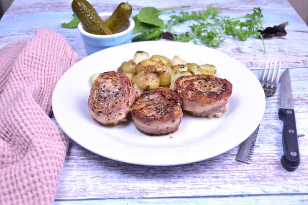 Bacon Wrapped Pork Medallions-Served on White Plate With Parsley Potatoes and Pickles
