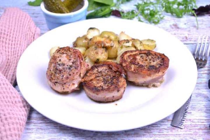 Serve Tender bacon-wrapped pork tenderloin medallions plated with golden parsley baby potatoes.