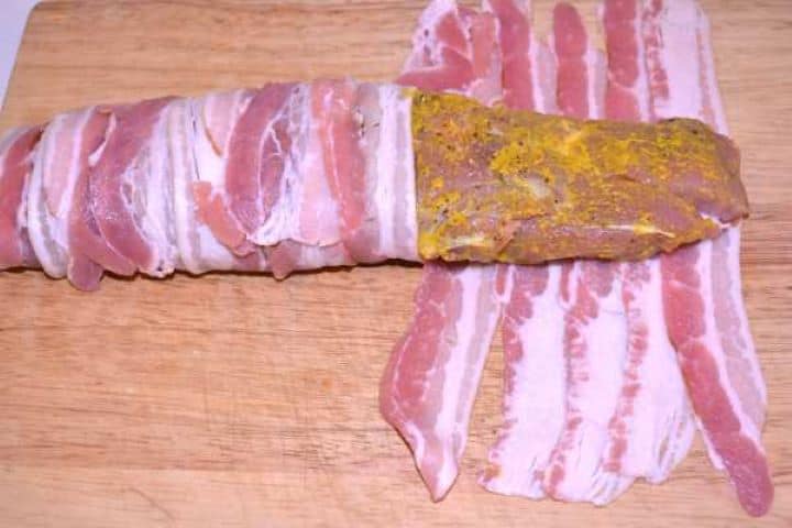 Wrapping Wrapping smoked bacon strips tightly around the seasoned pork tenderloin fillet.