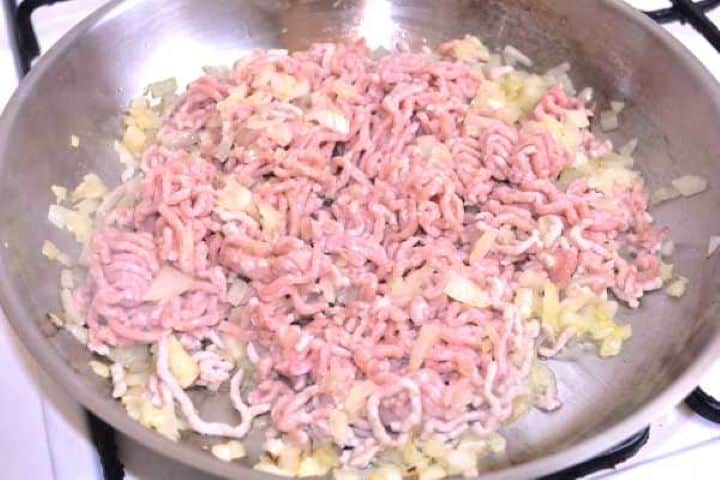 Mince Browning minced pork in a pan with sautéed onions for the savory Turkish moussaka meat sauce.