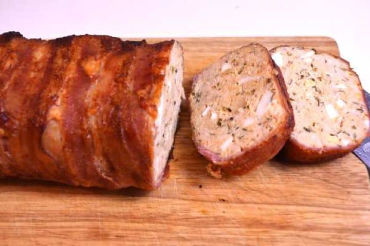 Serve Tender bacon wrapped turkey meatloaf sliced and garnished with fresh parsley on a wooden serving board.