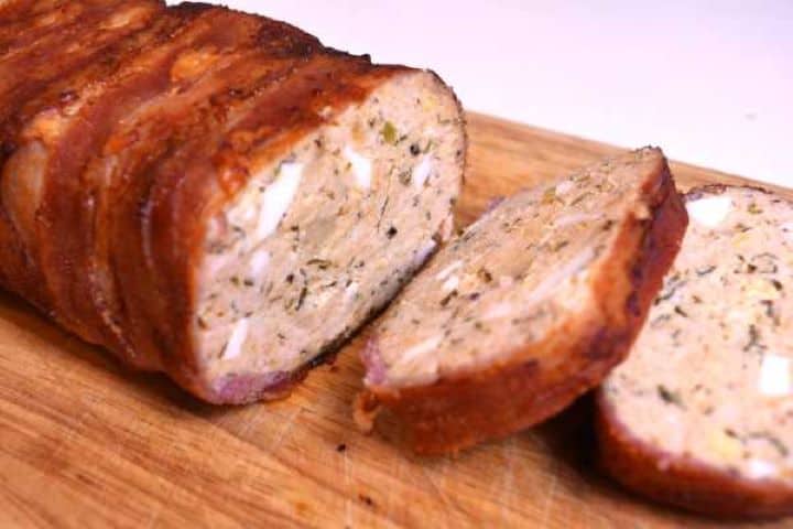 Served Bacon-wrapped turkey meatloaf sliced on the chopping board.